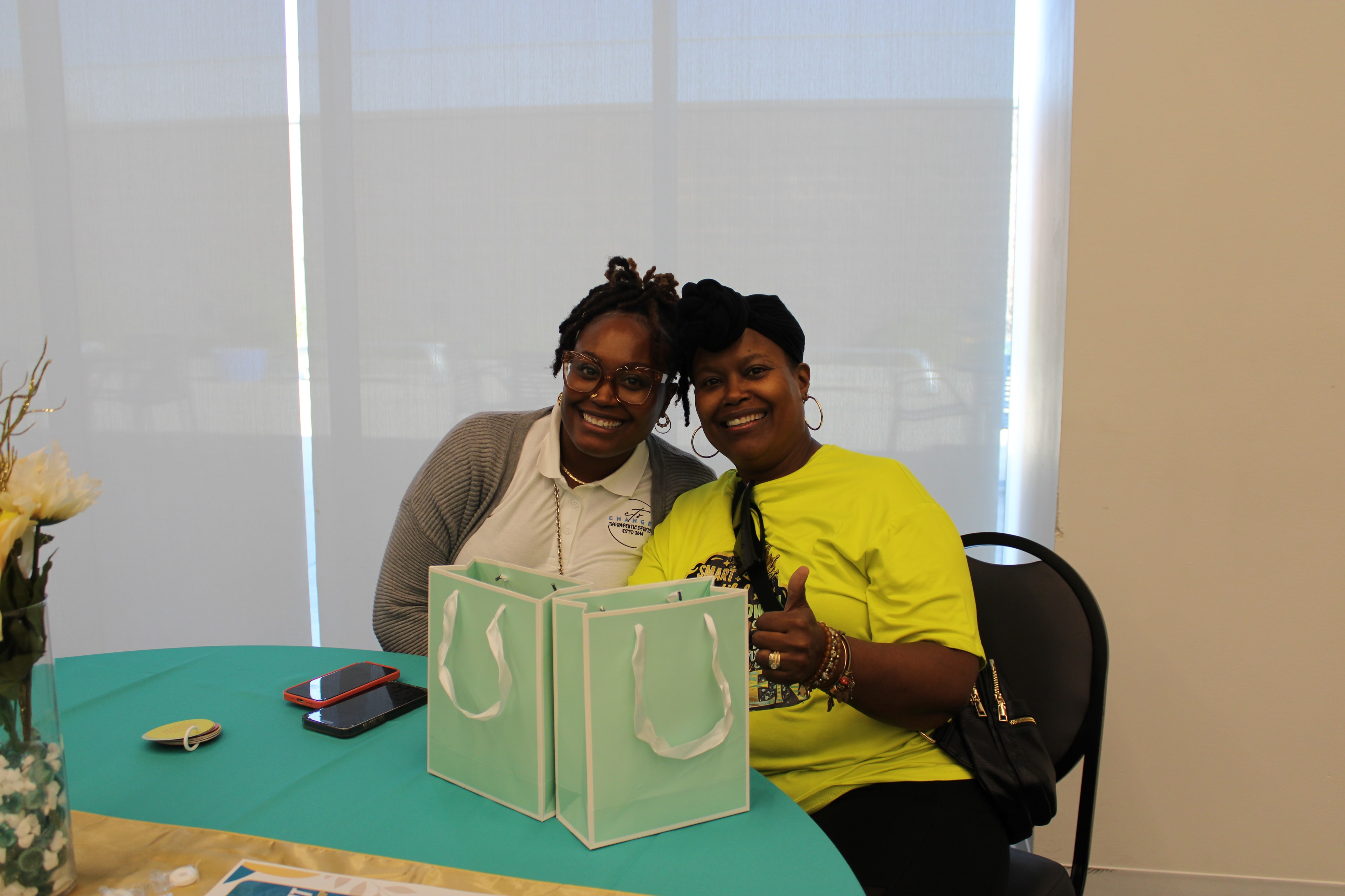 Two event attendees seated together at a decorated table with gift bags