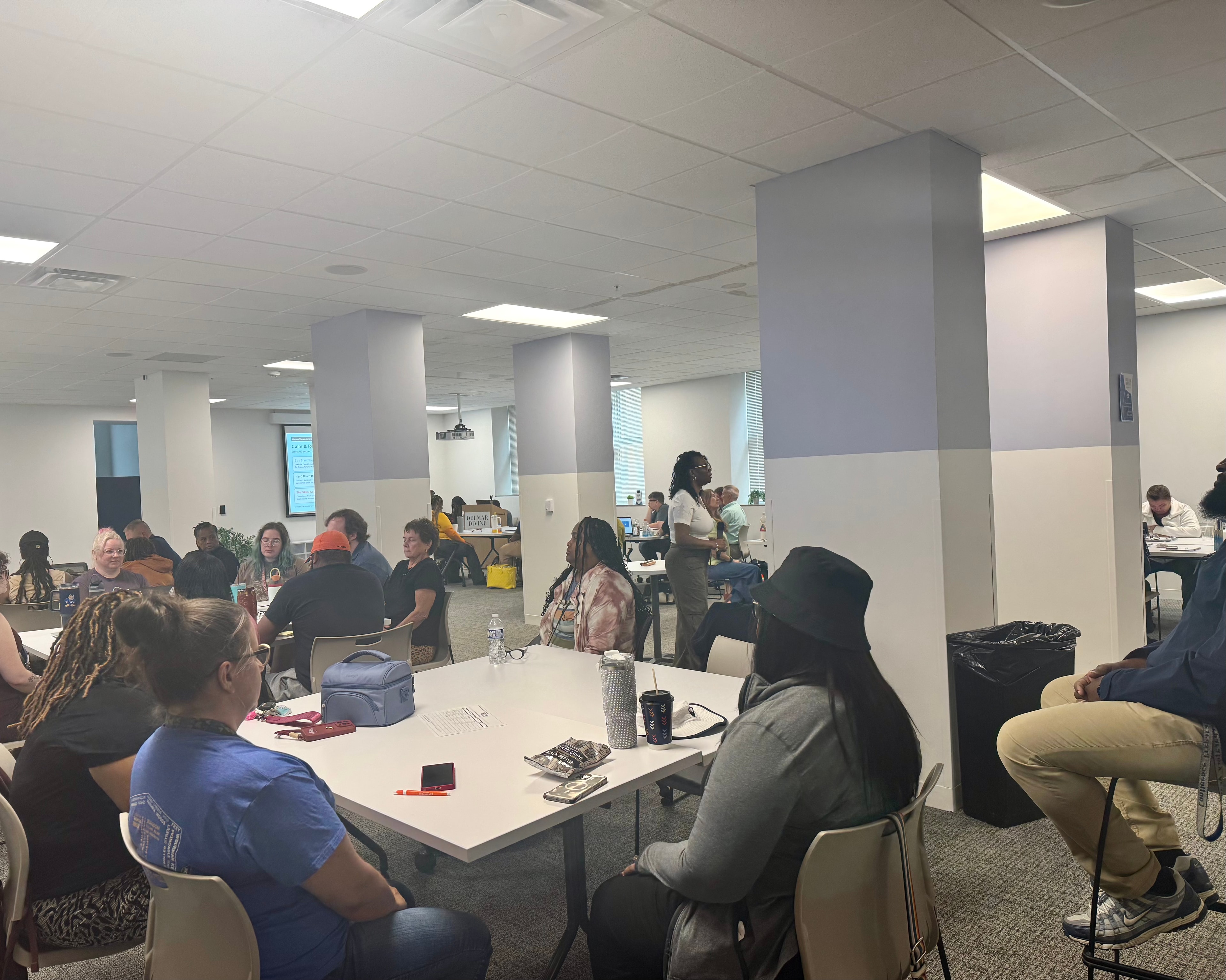 Community members seated at tables during an indoor training session