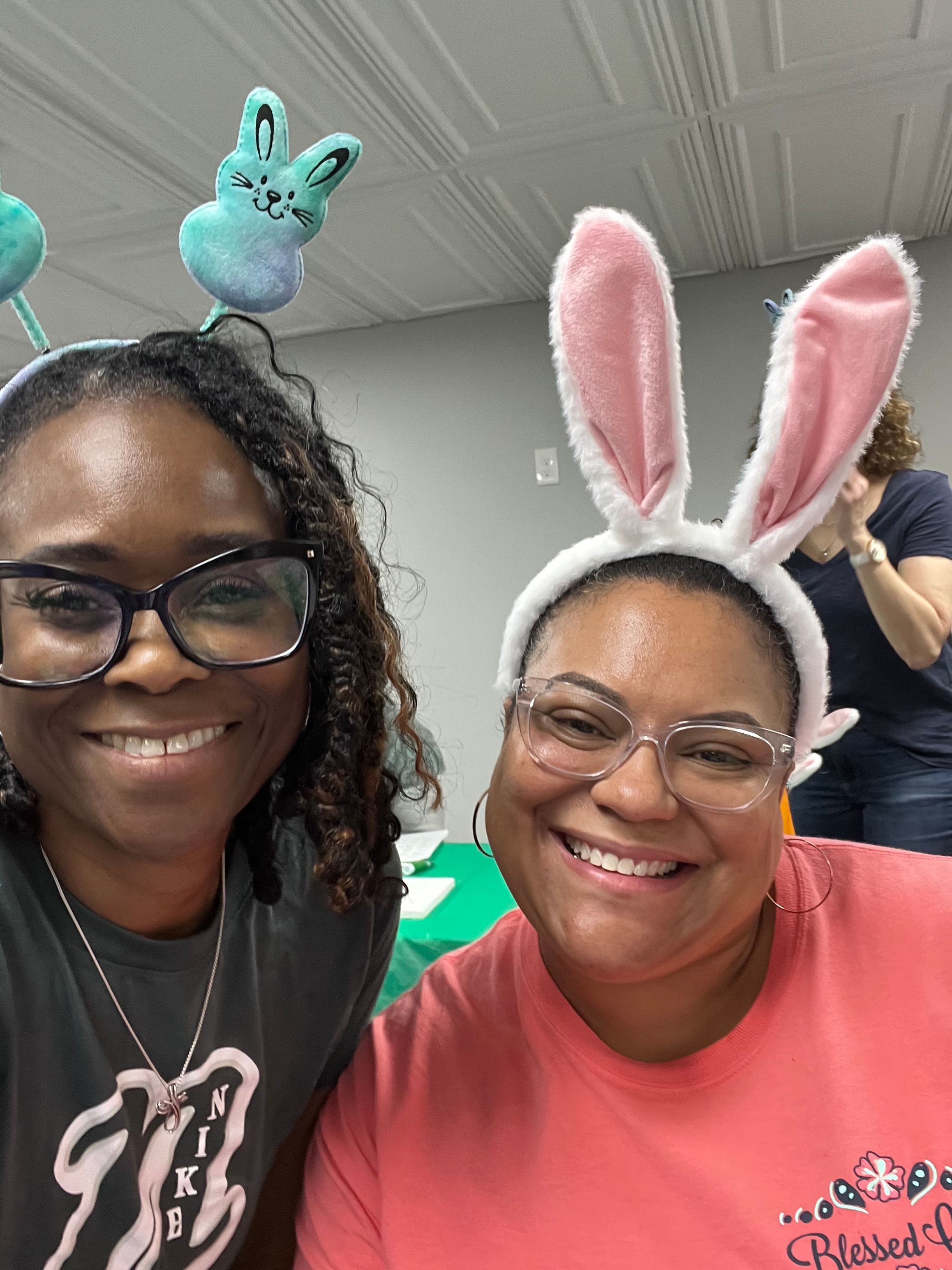 Two smiling participants wearing bunny ears at an Easter event