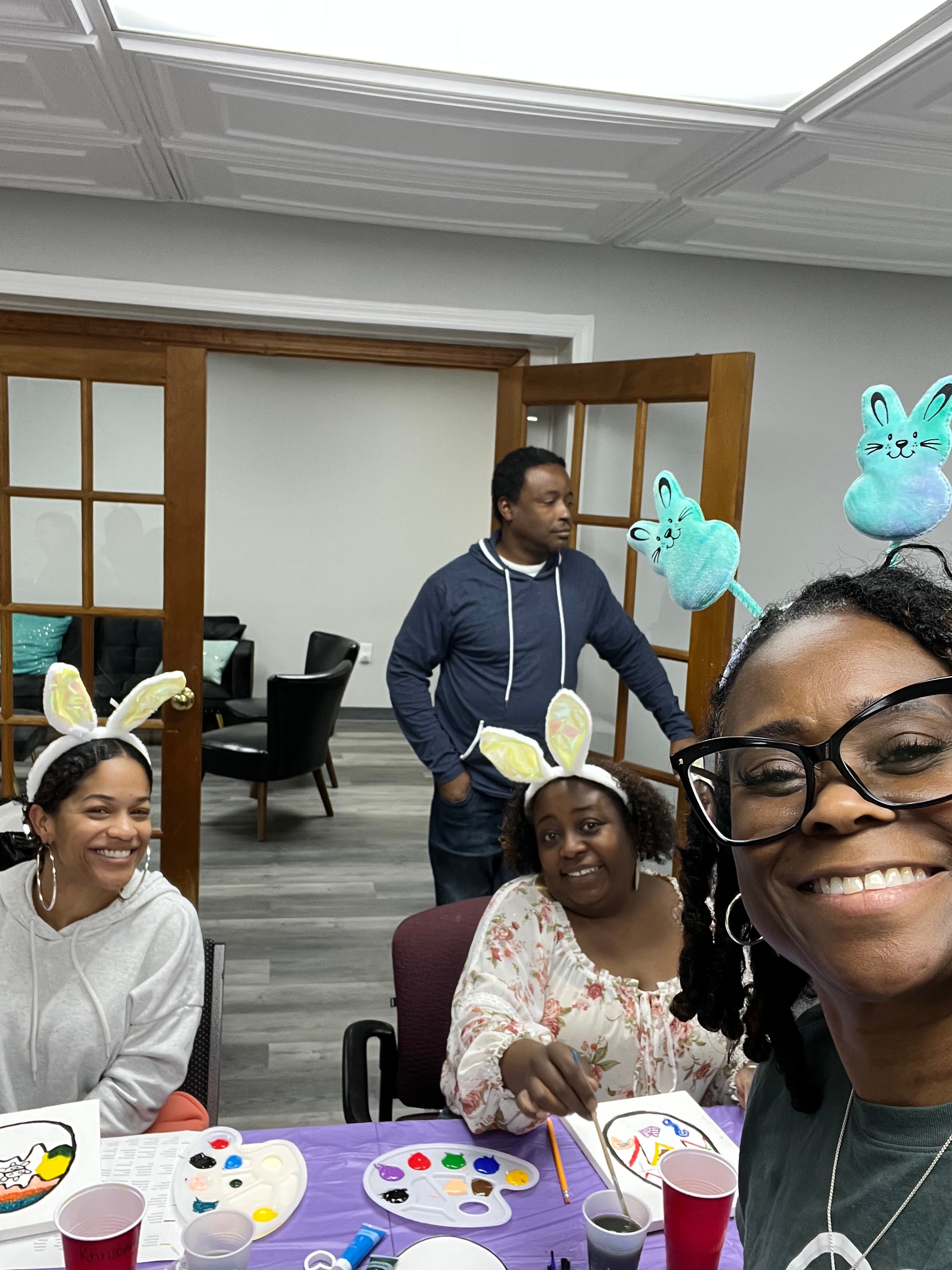 Participants wearing bunny ears while painting together at an Easter activity