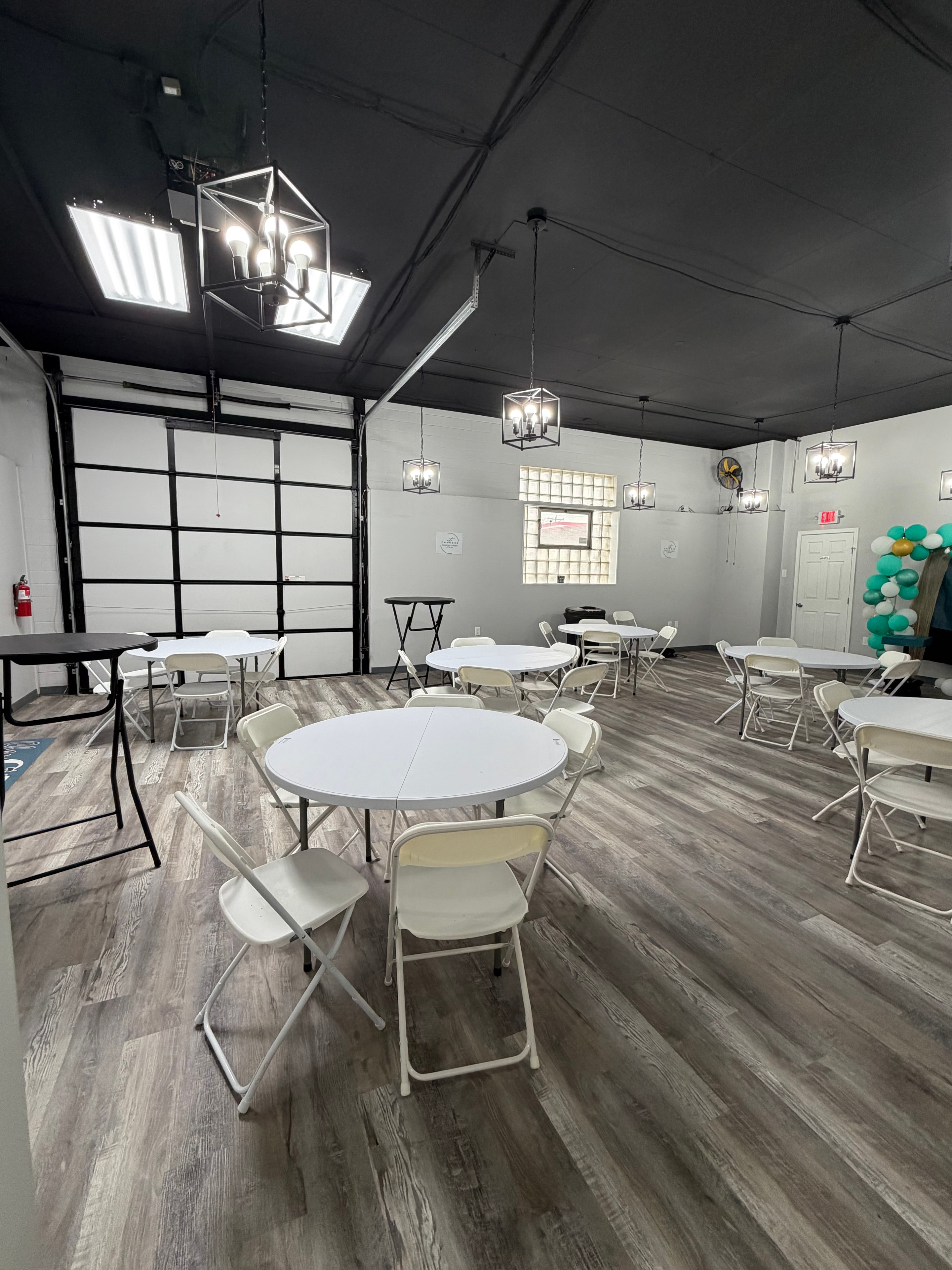Event space interior with round tables, pendant lighting, and garage door