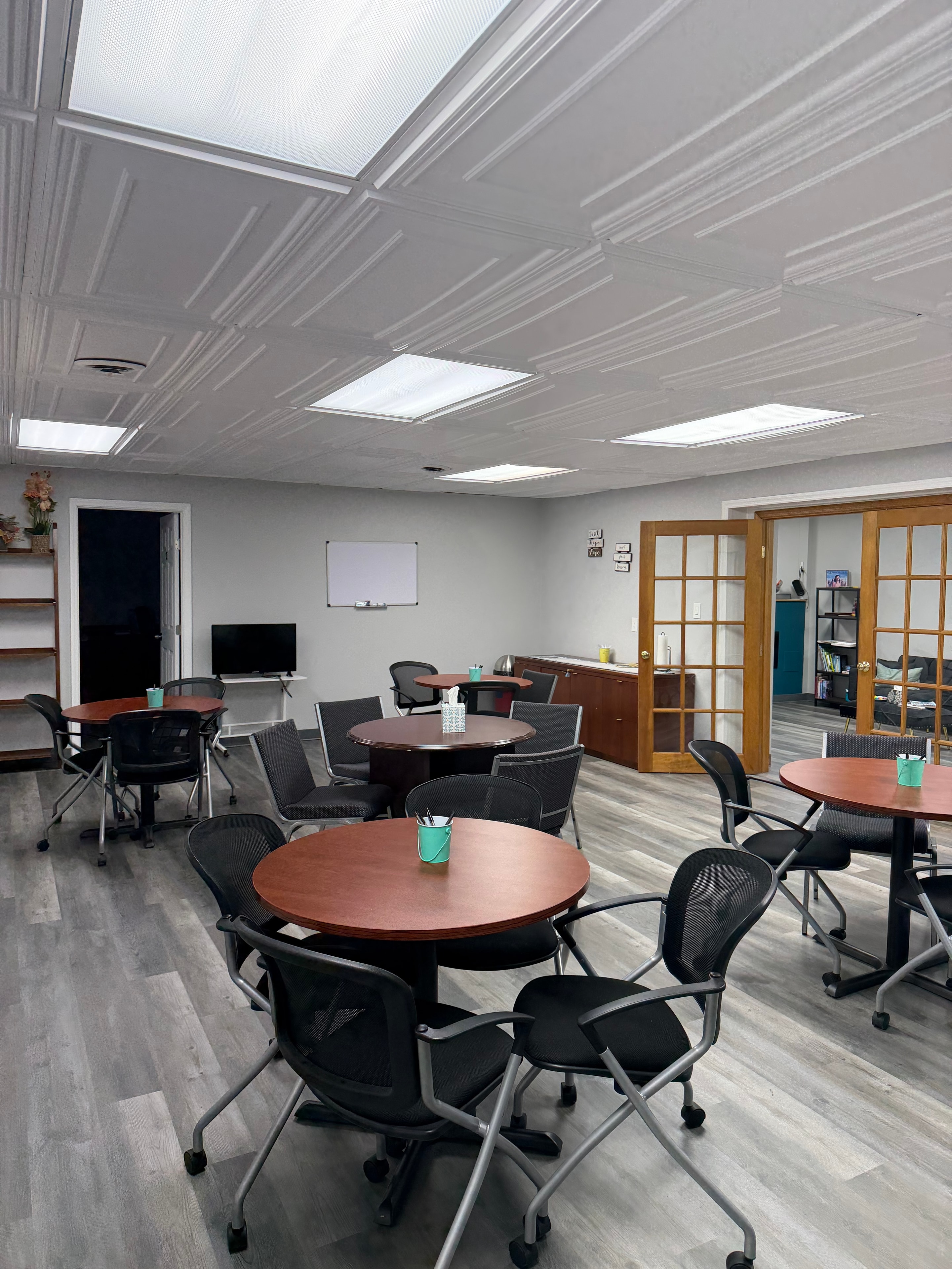 Event space with round tables, black chairs, whiteboard, and French doors